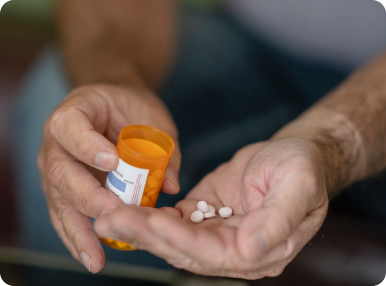 Man holding small white pills.